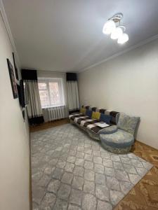 ein Wohnzimmer mit einem Sofa und einem Fenster in der Unterkunft 2-х комнатная Ауезова in Öskemen