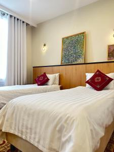 two beds in a hotel room with red pillows at Hotel Jipek Joli in Nukus