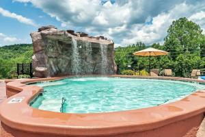 a swimming pool with a waterfall and an umbrella at Bear Tracks in Gatlinburg
