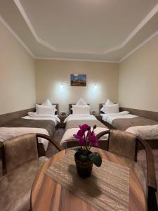 ein Zimmer mit 4 Betten und einem Tisch mit Blumen darauf in der Unterkunft Khan Palace Hotel in Yakkasaray