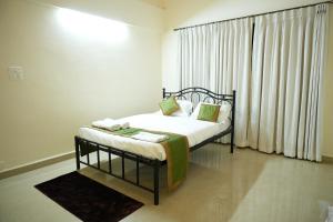 a bedroom with a bed and a window with curtains at Shri Mahamaya in Panaji