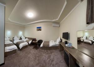 a hotel room with two beds and a flat screen tv at Khan Palace Hotel in Yakkasaray