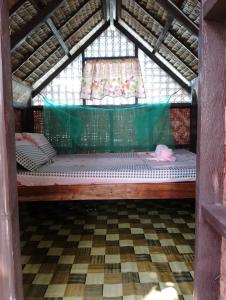 ein kleines Bett in einem Zimmer mit Fenster in der Unterkunft LHOYJEAN Garden Hostel in Batuan