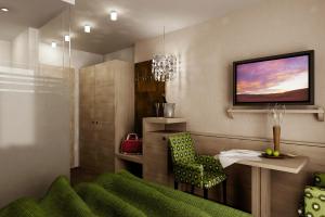 een woonkamer met een groene stoel en een televisie bij Hotel Garni Hubertus in Tirolo