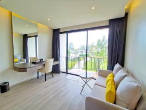 een woonkamer met een bank, een tafel en een bureau bij De VeraNiO Resort in Ban Mai Rut