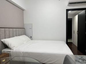 1 dormitorio con cama blanca y espejo en Aeon Tower 2627, en Davao City