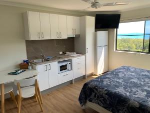 a bedroom with a bed and a kitchen with white cabinets at Island Views in Airlie Beach
