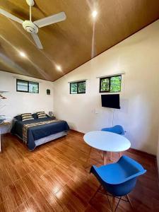 a bedroom with a bed and a table and blue chairs at CASA NOIL, Beautiful Eco House near the beach! in Puerto Viejo