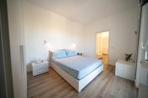 a white bedroom with a bed and a wooden floor at Dimore Capirro Charming Family House in Trani
