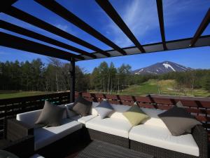 a couch on a deck with a view of a mountain at Villa the Club Karuizawa in Naganohara