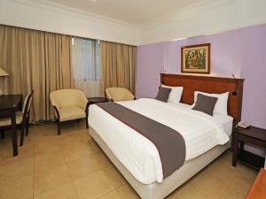 ein Hotelzimmer mit einem großen Bett und einem Schreibtisch in der Unterkunft Super OYO Collection O 91898 Series Hotel Kuningan in Jakarta