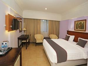 a hotel room with a bed and a desk at Super OYO Collection O 91898 Series Hotel Kuningan in Jakarta