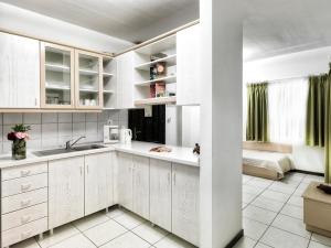 a kitchen with white cabinets and green curtains at Elia Apartments in Afitos