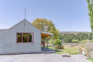 a small house with a red window and a picnic table at Mount Cook Station Shearers Quarters Lodge in Lake Tekapo