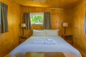 een slaapkamer met een bed met twee handdoeken erop bij Mount Cook Station Huts in Lake Tekapo