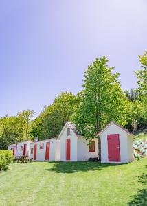 una fila de edificios blancos con puertas rojas en un campo de césped en Mount Cook Station Huts en Lake Tekapo