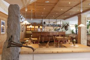 a restaurant with wooden tables and a bar at Landhotel Tharerwirt in Valdaora