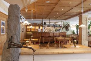 un restaurante con mesas de madera y un bar en Landhotel Tharerwirt, en Valdaora
