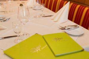 a table with green menus and wine glasses on it at Parkhotel Waldlust in Häusern