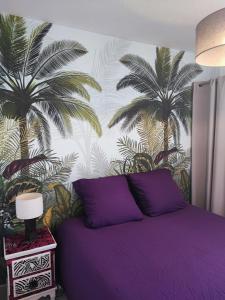 a bedroom with a purple bed with palm trees on the wall at La Perle Marine, joli appartement avec 1 chambre, Cosy et rénové à 200 m de la plage, vue Marina des Quilles, parking et Wifi in Sète