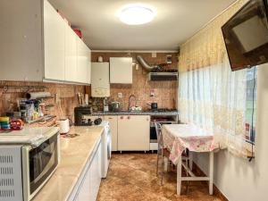a kitchen with white cabinets and a table in it at Casa Petruta Dambovicioara in Podu Dîmboviţei