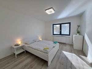 a white bedroom with a bed and a window at Veselá Lama Apartmány Janovice in Ostravice