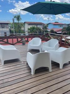 a group of white chairs and an umbrella on a deck at Casa Alta Gracia in Paramaribo