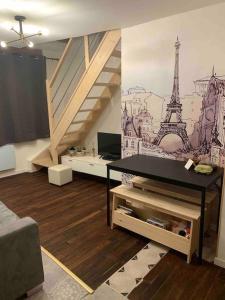 een woonkamer met een trap en een muurschildering van de eiffeltoren bij Appartement Duplex a 10 min de Disney in Coupvray
