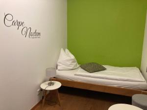 a small room with a bed with a green wall at Gleiseins in Naila