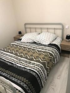 a bed with a black and white blanket and pillows at Maison chaleureuse au centre ville in Nérac