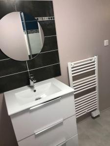 ein Badezimmer mit einem weißen Waschbecken und einem Spiegel in der Unterkunft Maison chaleureuse au centre ville in Nérac