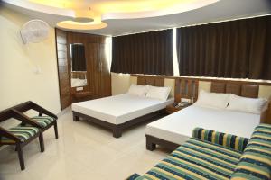 a hotel room with two beds and a chair at Hotel Shri Gourav in Bikaner