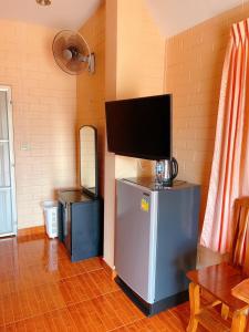 een woonkamer met een tv boven een koelkast bij Bunraksa Resort in Kamphaeng Phet