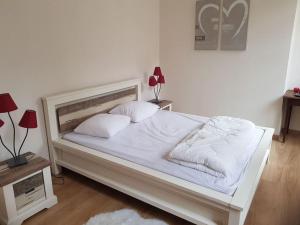 Una cama blanca con sábanas blancas y almohadas. en Le petit Conté - Maison calme en centre ville, en Sées