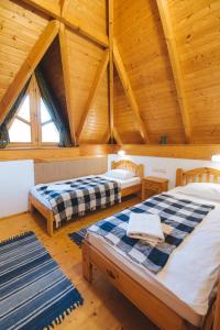 two beds in a room with wooden ceilings at Kormorán Vendégház in Tiszafüred