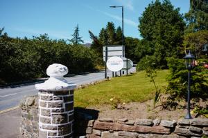 una statua di pietra su un muro accanto a una strada di Westlands of Pitlochry a Pitlochry