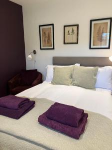 Un dormitorio con una gran cama blanca con toallas moradas. en The Burrow, en Wellesbourne