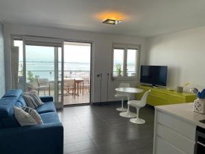 a kitchen and living room with a blue couch and a table at Costa Azzurra Aparment in Grado