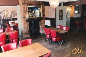un restaurant avec des chaises rouges, des tables et un miroir dans l'établissement The Globe Inn, à Tiverton