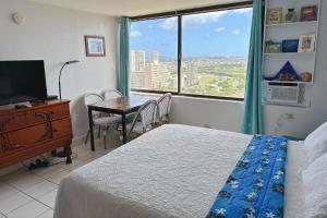 a bedroom with a bed and a table and a window at Waikiki Condo High Floor Views Beaches Convention Center in Honolulu
