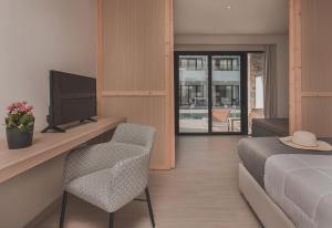 a bedroom with a bed and a tv and a chair at Cavo di Suites in Kalamaki