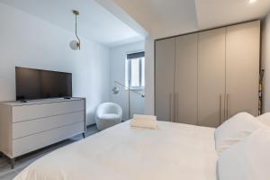 Un dormitorio con una gran cama blanca y un televisor. en Luxury property in Gzira just minutes away from the seafront and Restaurants, en Il-Gżira