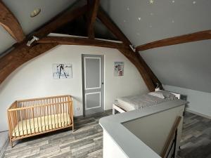 a bedroom with a crib in a attic at Maison de village chez Josy in Coudun