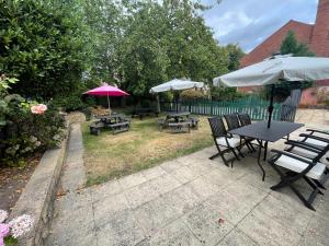 a patio with tables and chairs and umbrellas at Mansfield Lodge Hotel Ltd in Mansfield