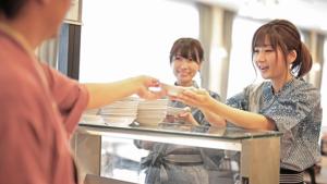 Deux femmes se tiennent devant un comptoir avec plaques dans l'établissement Kyukamura Tateyama, à Tateyama