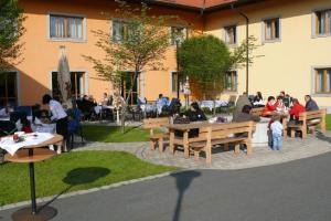 a group of people sitting at tables in a courtyard at Witikohof in Haidmühle