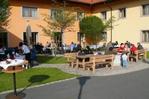 eine Gruppe von Personen, die an Tischen im Innenhof sitzen in der Unterkunft Witikohof in Haidmühle