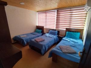a room with three beds and a window with blinds at Basant Villa in Wadi Musa