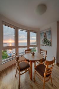 a dining room with a table and chairs and windows at Moana Lighthouse Apartment in Ahtopol