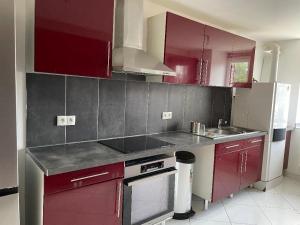 uma cozinha com armários vermelhos e um frigorífico branco em senechal em Lorette